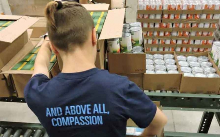 a person packs boxes of food as part of a service project with outward bound
